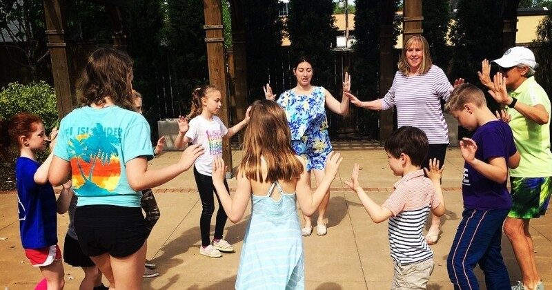 young students dancing outside in a circle
